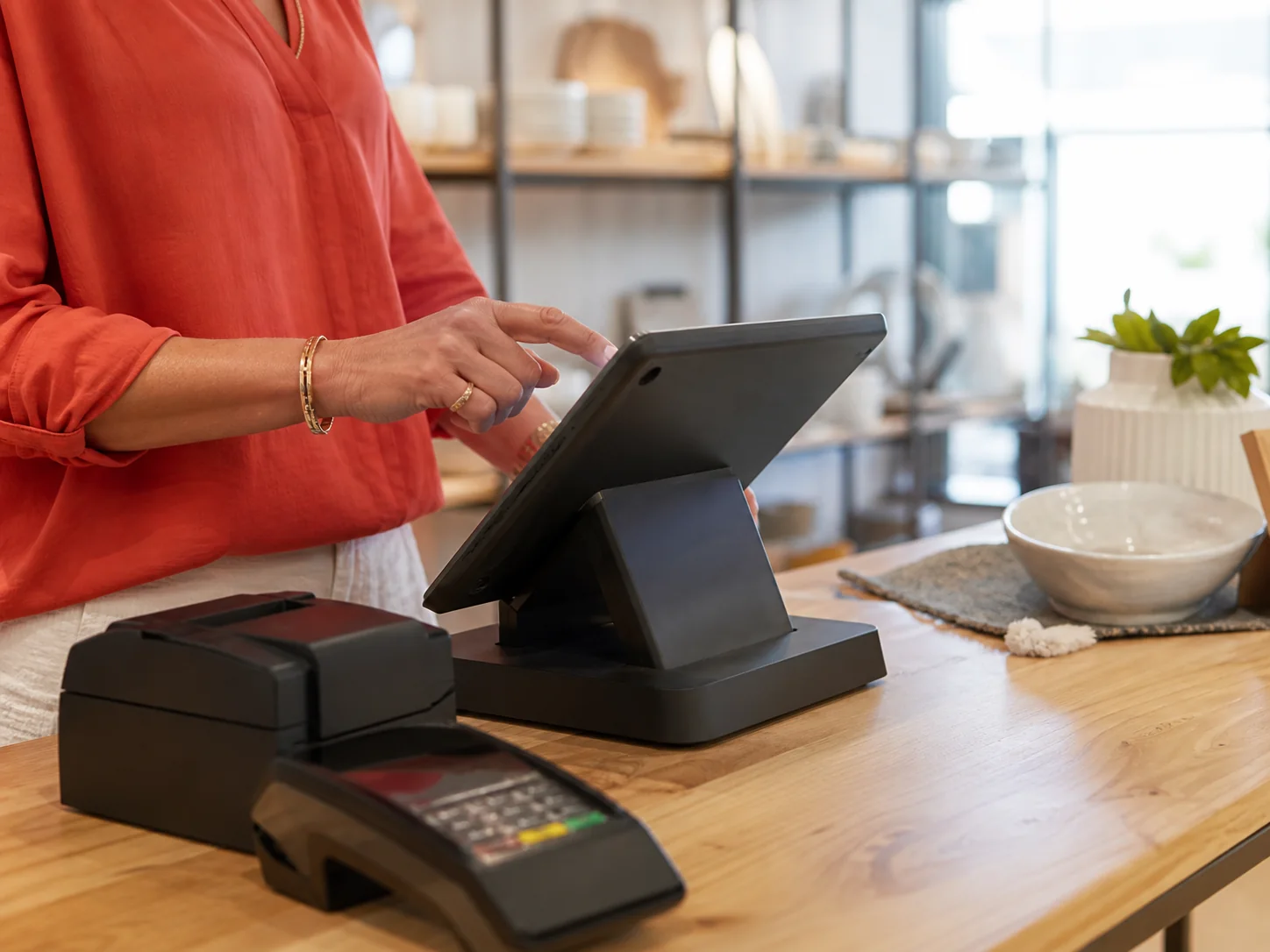 Retailer using a touchscreen point-of-sale terminal at a shop counter